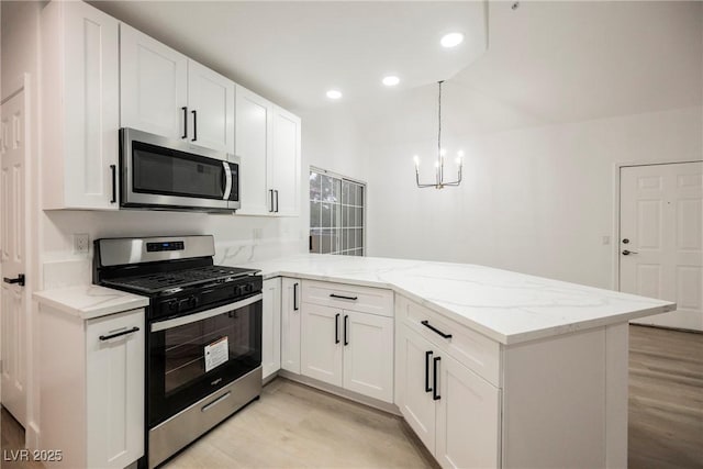 kitchen featuring appliances with stainless steel finishes, pendant lighting, white cabinetry, and a peninsula