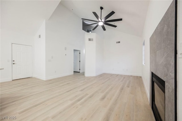 unfurnished living room with light wood-style floors, baseboards, high vaulted ceiling, and a tile fireplace