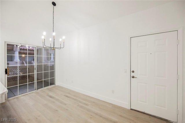 unfurnished dining area with baseboards, a chandelier, and wood finished floors