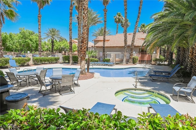 pool with a patio area, fence, and a hot tub