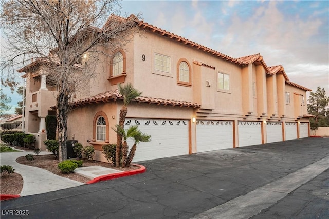 view of front facade featuring cooling unit, driveway, and stucco siding