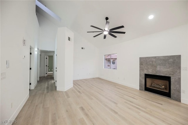 unfurnished living room with light wood-type flooring, a tile fireplace, a ceiling fan, and baseboards