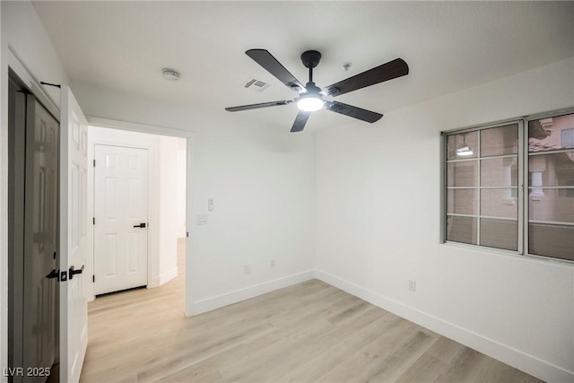 empty room featuring baseboards, a ceiling fan, visible vents, and light wood-style floors