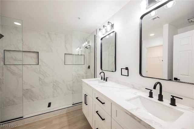 full bathroom featuring a marble finish shower, visible vents, a sink, and wood finished floors