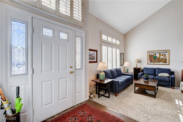 foyer entrance featuring high vaulted ceiling and wood finished floors