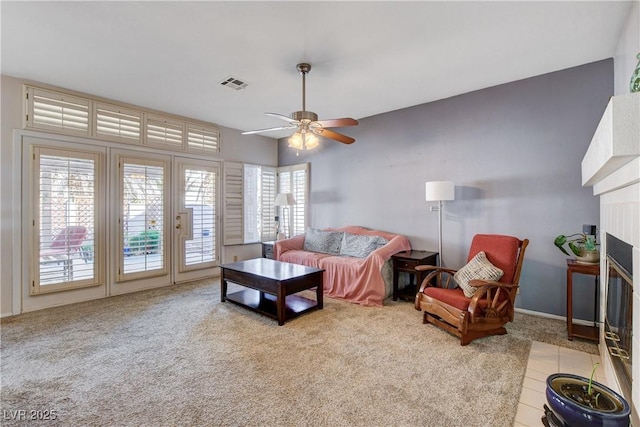 living room with a fireplace with flush hearth, light colored carpet, visible vents, and a ceiling fan