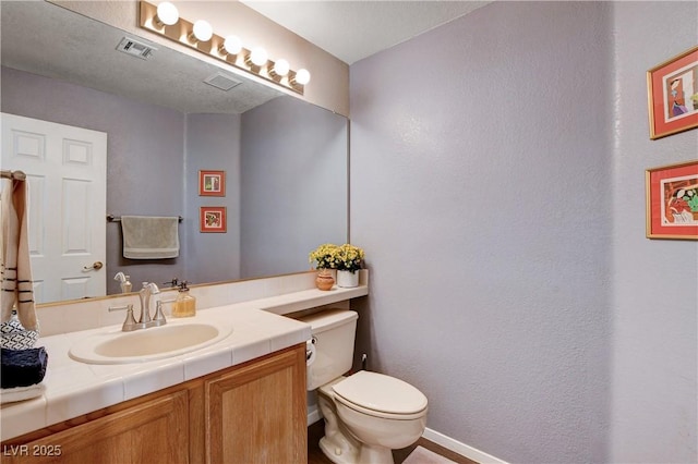 bathroom with visible vents, vanity, and toilet