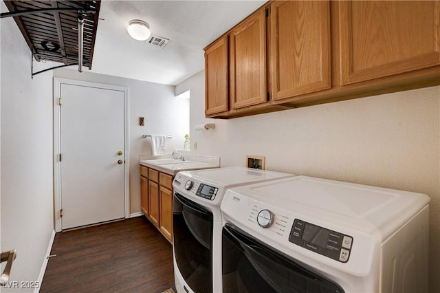 laundry room featuring cabinet space, visible vents, dark wood-type flooring, washing machine and clothes dryer, and a sink