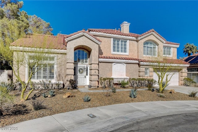 mediterranean / spanish-style home with a garage, a tiled roof, driveway, stucco siding, and a chimney