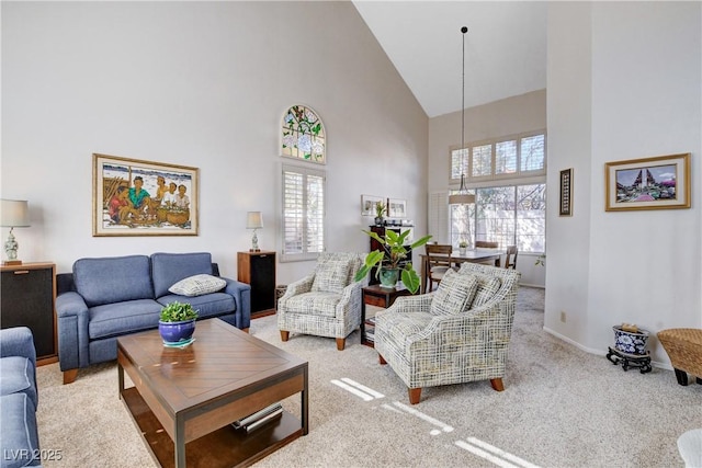 carpeted living area featuring baseboards and high vaulted ceiling