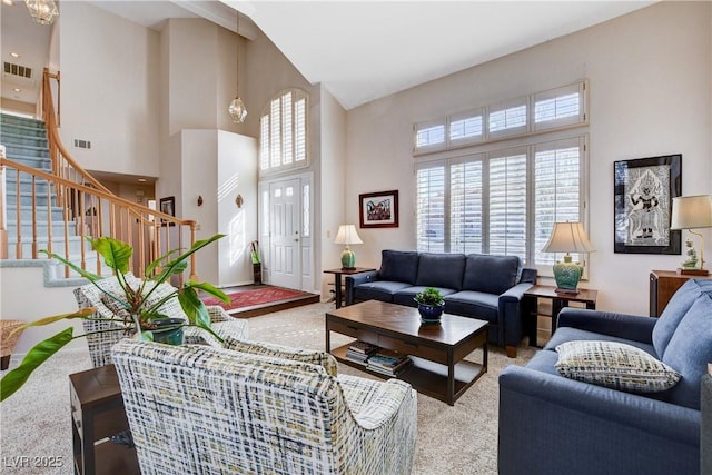 living room featuring stairs, a high ceiling, visible vents, and light colored carpet