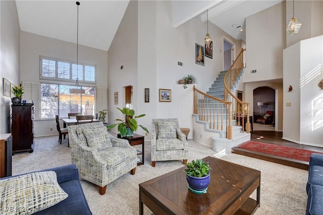 living room with arched walkways, a towering ceiling, baseboards, stairway, and carpet