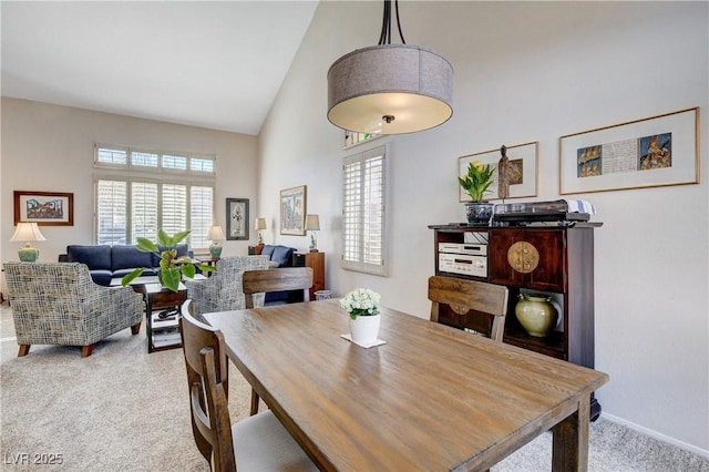 dining space with high vaulted ceiling, a wealth of natural light, light carpet, and baseboards