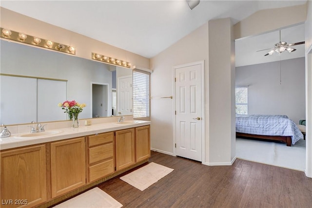 ensuite bathroom featuring plenty of natural light, lofted ceiling, a sink, and ensuite bathroom