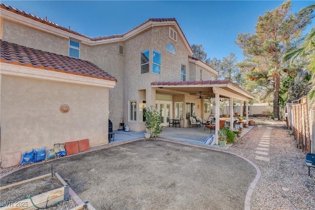 rear view of property featuring a patio, a fenced backyard, ceiling fan, a tiled roof, and stucco siding