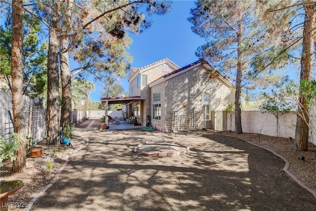 back of house featuring a fenced backyard, a patio, a tiled roof, and stucco siding