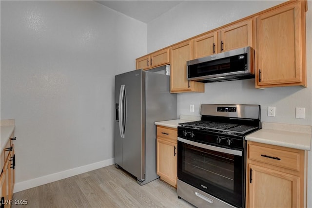 kitchen featuring light brown cabinets, baseboards, stainless steel appliances, and light countertops