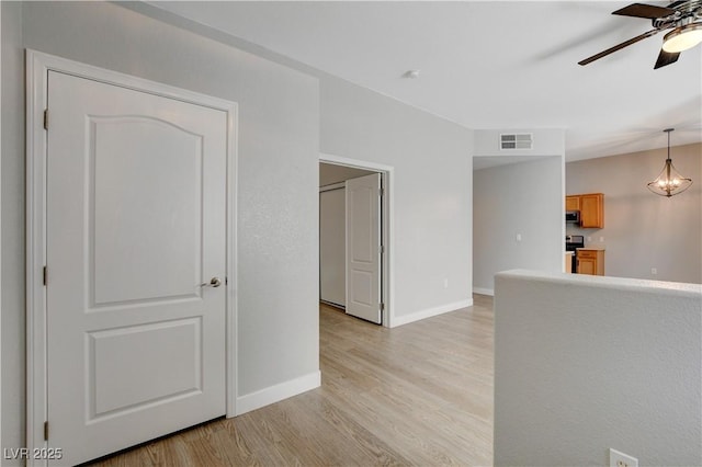 spare room featuring light wood-type flooring, visible vents, ceiling fan, and baseboards