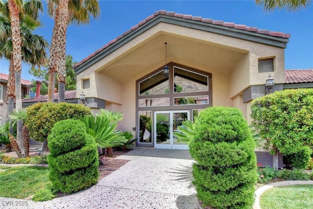 view of exterior entry with a tile roof and stucco siding