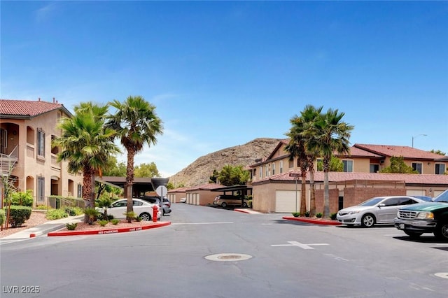 view of road featuring a residential view, curbs, sidewalks, a mountain view, and street lights