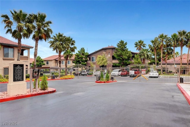 view of road with a residential view, a gate, curbs, and a gated entry