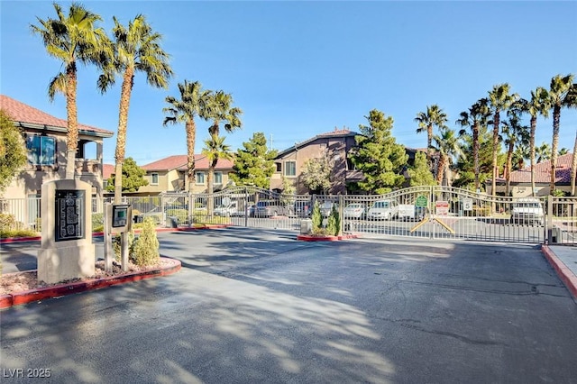 view of street featuring curbs, a gated entry, a residential view, and a gate