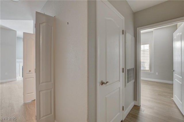 corridor with light wood-style flooring and baseboards