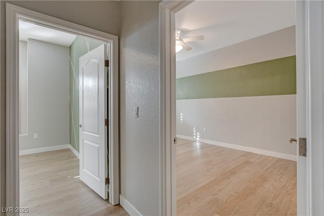 hall with light wood-style flooring and baseboards