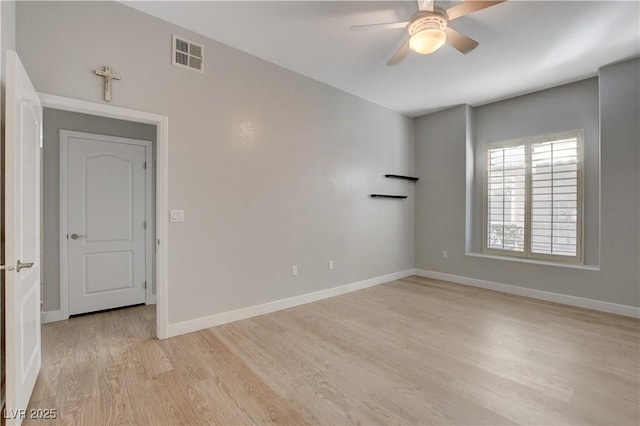 unfurnished room with light wood finished floors, a ceiling fan, visible vents, and baseboards