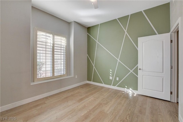 empty room featuring wood finished floors, a ceiling fan, and baseboards