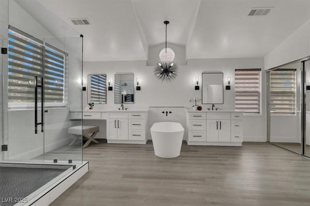 full bath with wood finished floors, two vanities, a sink, vaulted ceiling, and visible vents