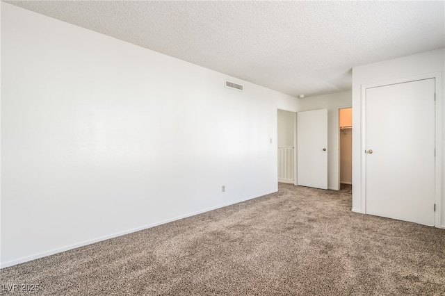 2667 Aracatuba Ave, Las Vegas, NV 89121 - unfurnished bedroom featuring carpet floors, a textured ceiling, baseboards, a spacious closet, and visible vents