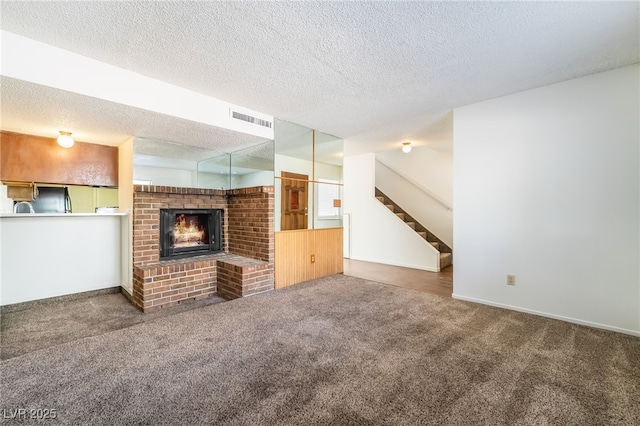 2667 Aracatuba Ave, Las Vegas, NV 89121 - unfurnished living room featuring visible vents, stairs, a brick fireplace, a textured ceiling, and carpet flooring