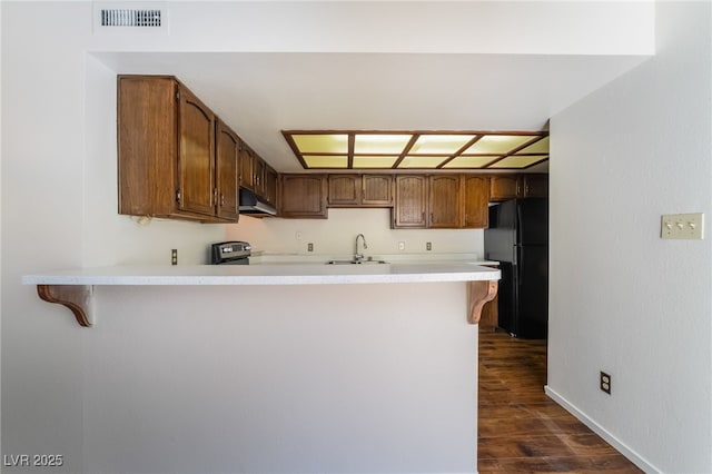 2667 Aracatuba Ave, Las Vegas, NV 89121 - kitchen featuring freestanding refrigerator, a peninsula, under cabinet range hood, visible vents, and dark wood-style floors
