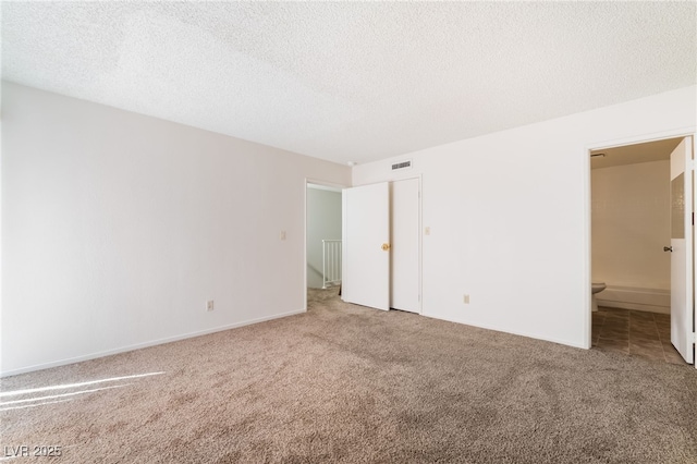 2667 Aracatuba Ave, Las Vegas, NV 89121 - unfurnished bedroom featuring a textured ceiling, visible vents, baseboards, connected bathroom, and carpet
