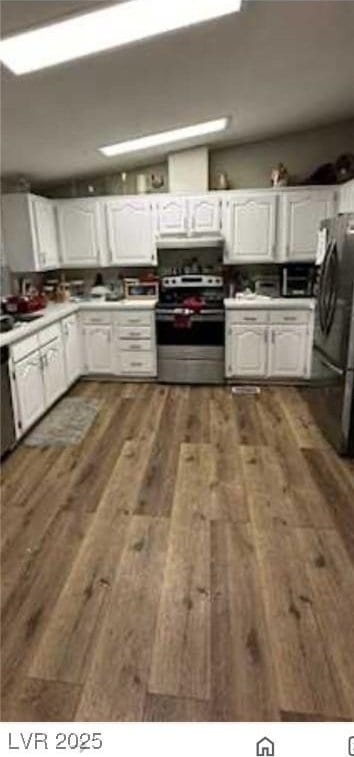 kitchen featuring dark wood-style floors, white cabinetry, freestanding refrigerator, and stainless steel range with electric cooktop