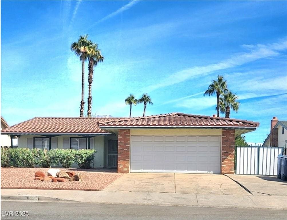 view of front of property featuring an attached garage, a tile roof, concrete driveway, and stucco siding