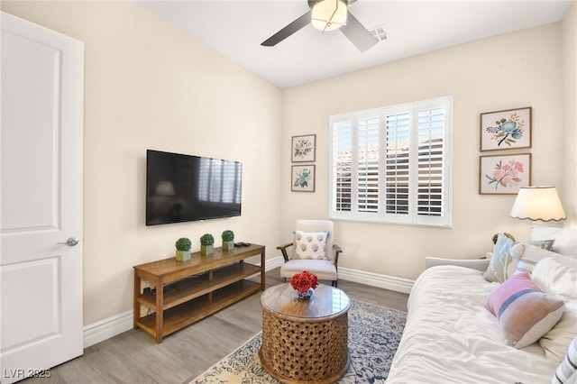 living room with ceiling fan, visible vents, baseboards, and wood finished floors