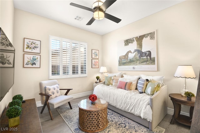 living room with baseboards, wood finished floors, visible vents, and ceiling fan