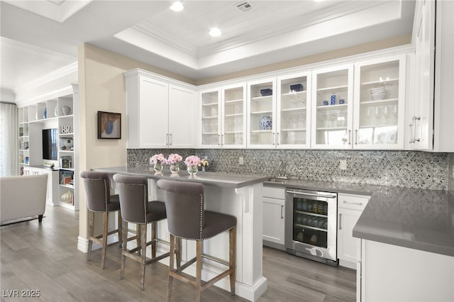 kitchen with wine cooler, backsplash, a kitchen breakfast bar, and crown molding