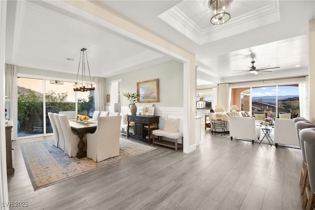 dining area with a healthy amount of sunlight, crown molding, a tray ceiling, and wood finished floors