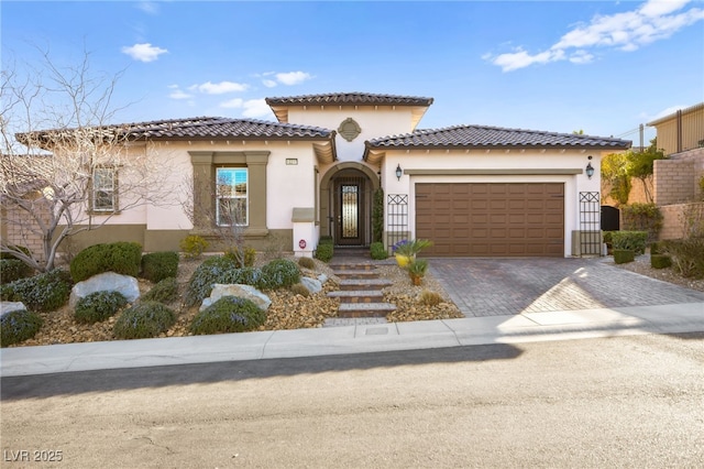 mediterranean / spanish-style house with a tiled roof, stucco siding, driveway, and a garage