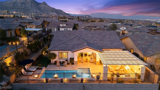 back of house featuring a tile roof, a patio area, a fenced backyard, and stucco siding