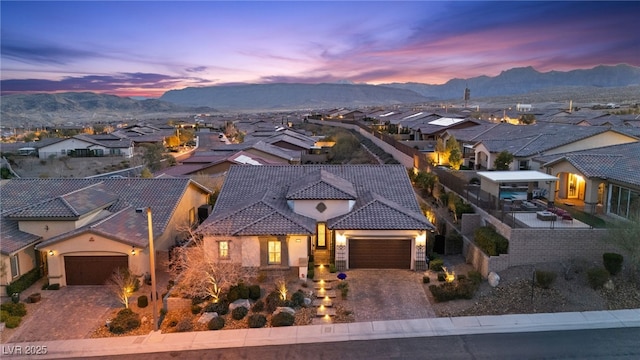 view of front of house with a residential view, stucco siding, a garage, a tile roof, and a mountain view