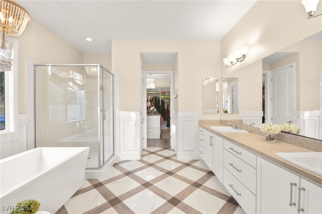 bathroom featuring a shower stall, a freestanding tub, a wainscoted wall, and a sink