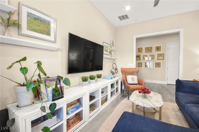 living room featuring visible vents, baseboards, and wood finished floors