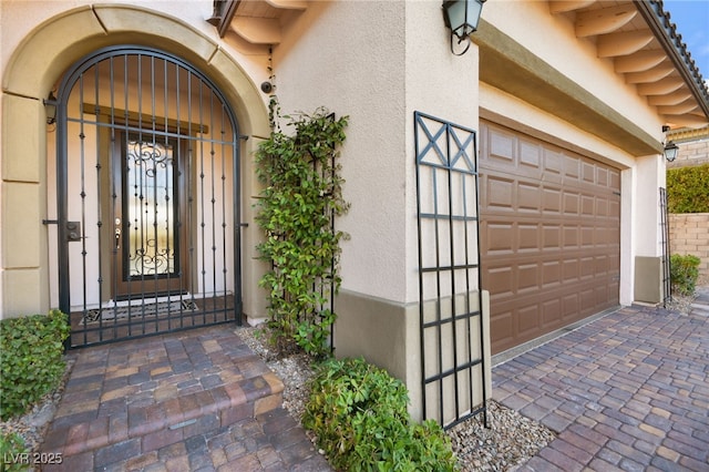 doorway to property featuring stucco siding, driveway, and a garage