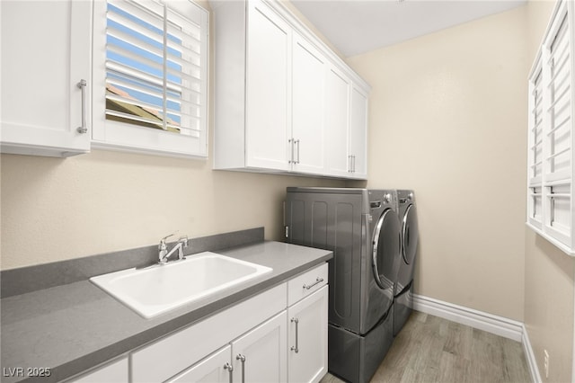 washroom with a sink, cabinet space, separate washer and dryer, light wood-style floors, and baseboards