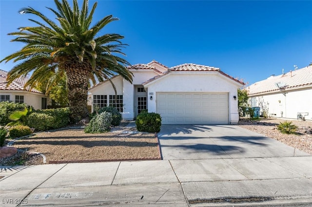 mediterranean / spanish home with concrete driveway, an attached garage, a tiled roof, and stucco siding