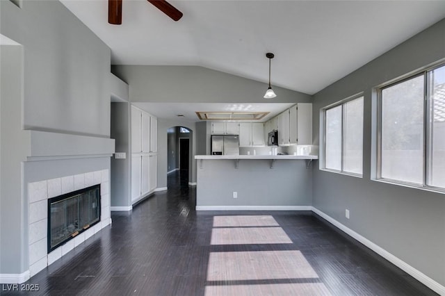 kitchen with black microwave, a peninsula, white cabinets, light countertops, and stainless steel fridge